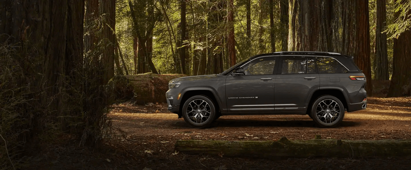A side profile of the two-row 2022 Jeep Grand Cherokee L Summit Reserve against a backdrop of trees, allowing the viewer to estimate its length.